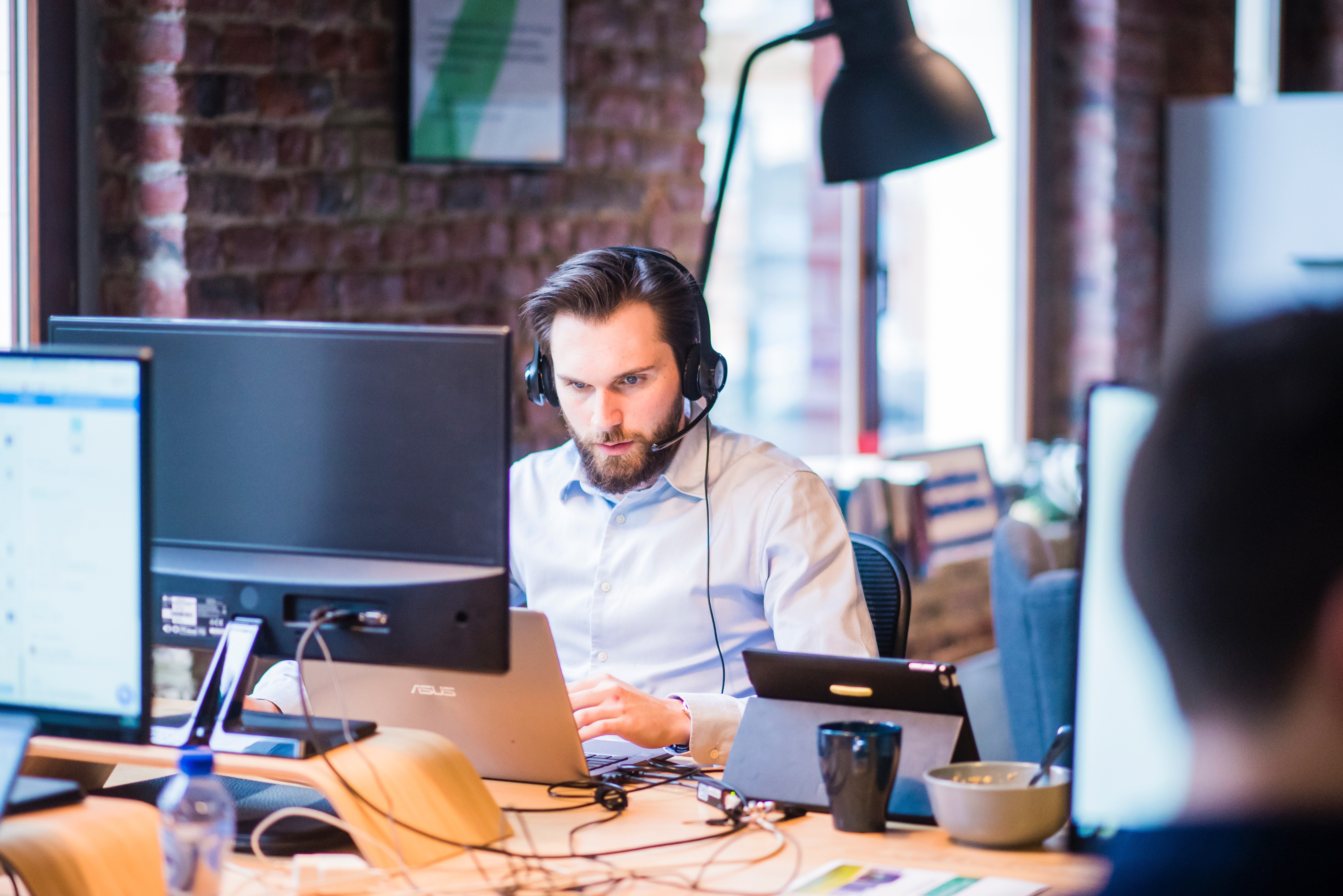 Man with phone headset on working at shared desk