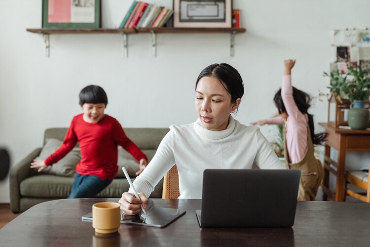 Woman working from home with children in background 