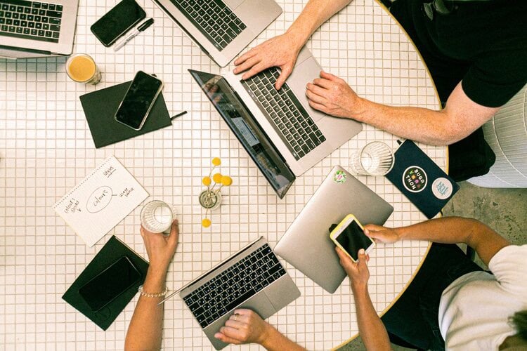 Overhead photo of business meeting with 5 laptops 