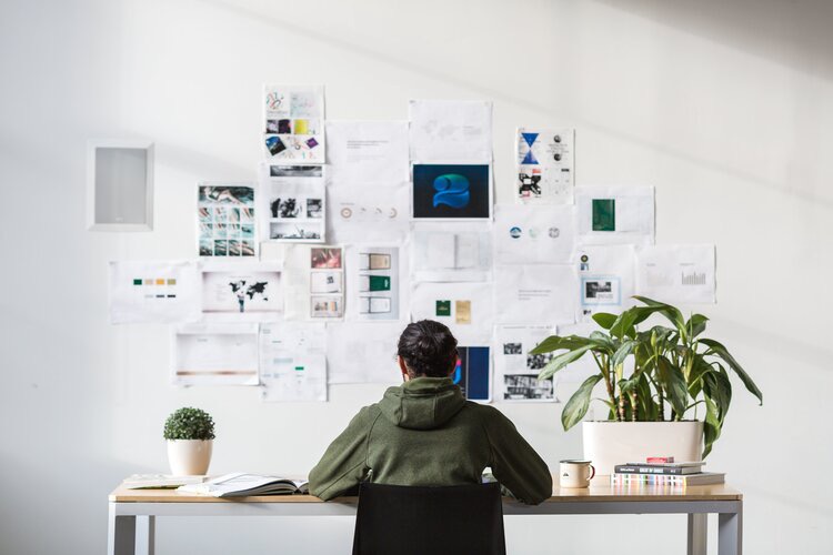 Man sits in front of a cluttered wall with various pieces of paper