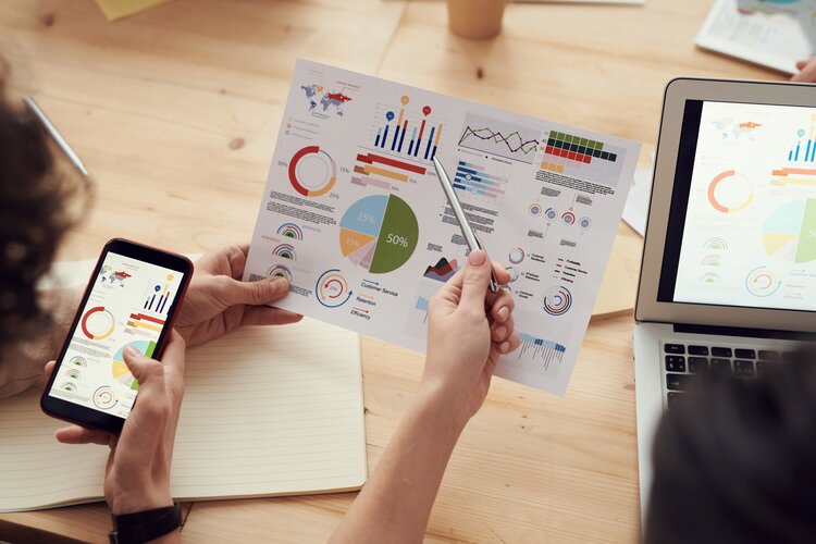 Two people with graphs and charts on mobile device and paper