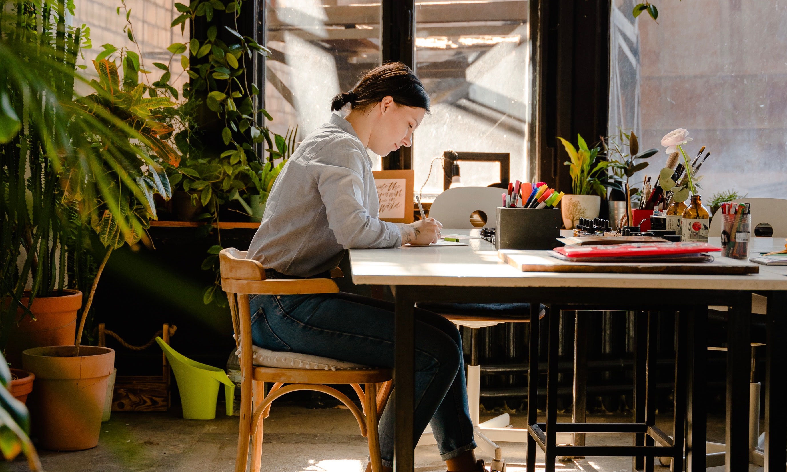 A home office with multiple plants in foreground and background